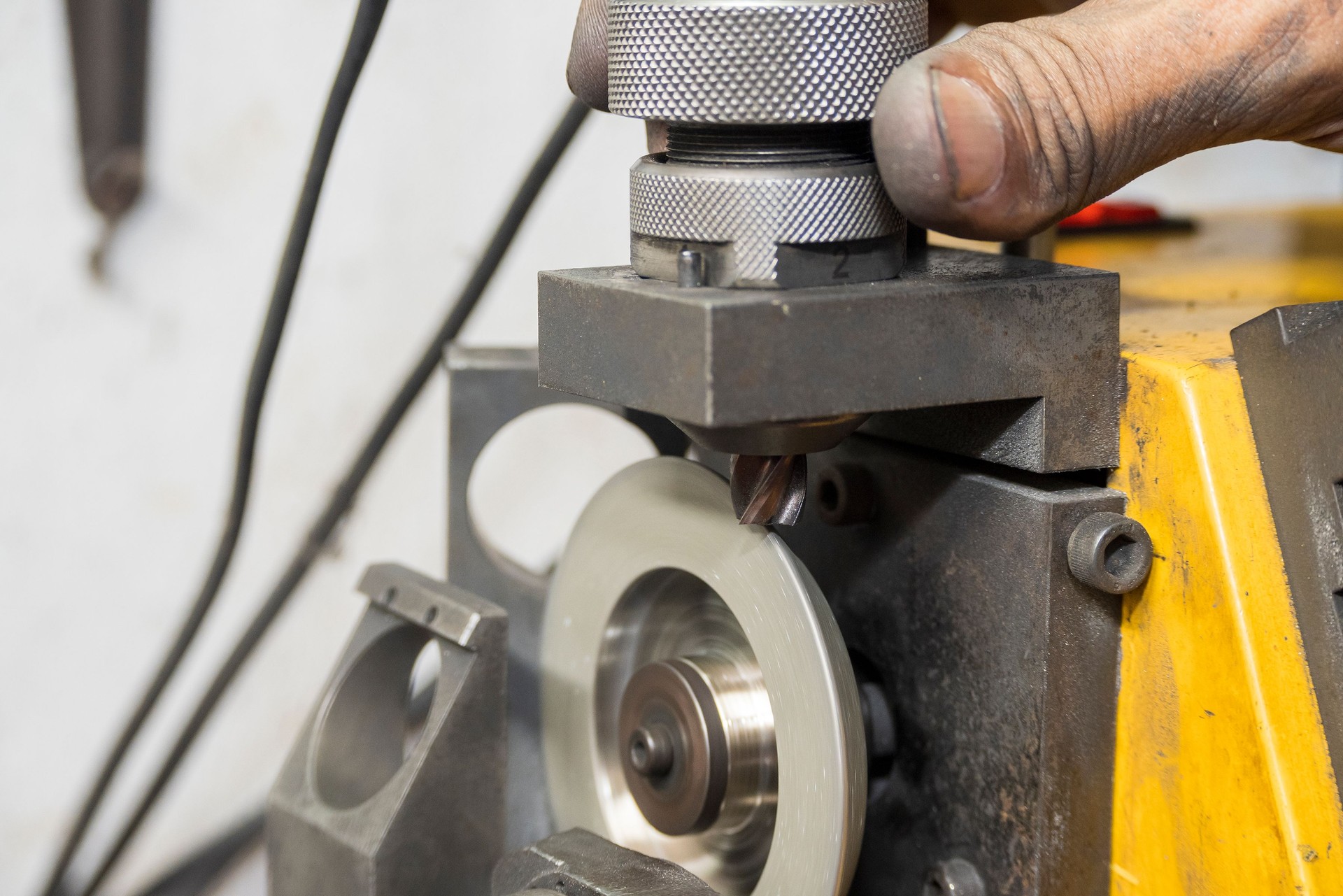 The worker regrinding the end mill tool with end mill sharpening machine.